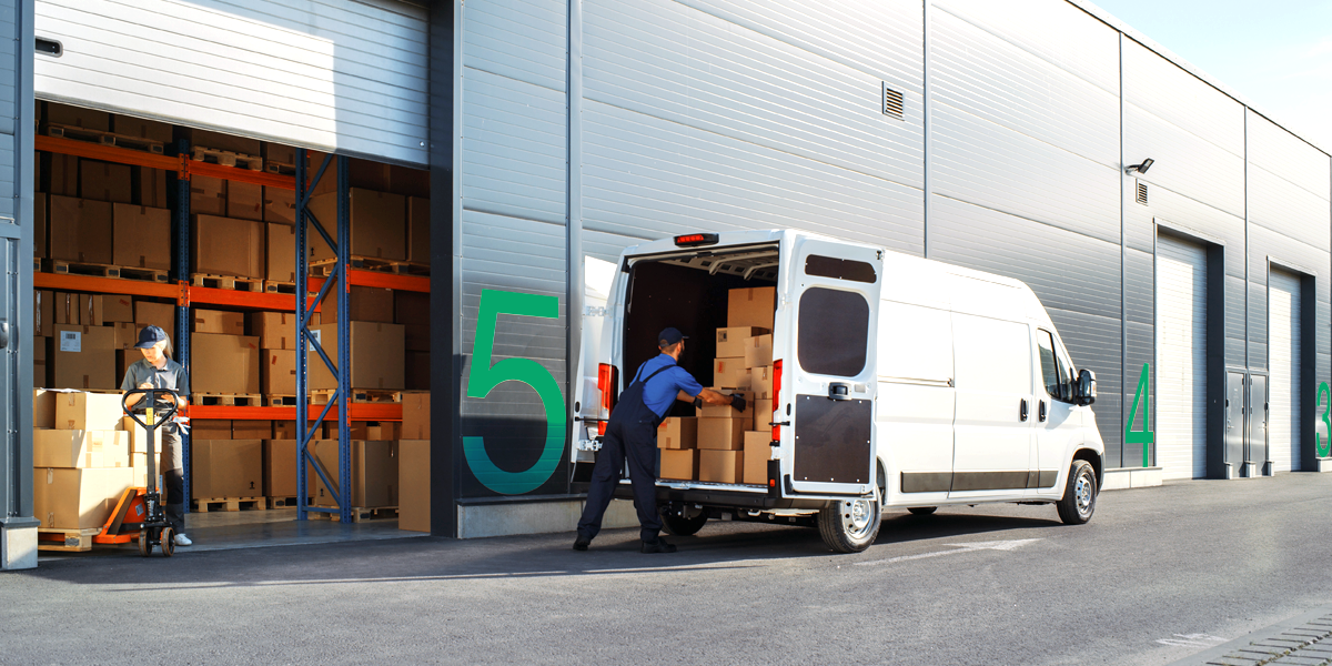 man loading boxes into the back of a van outside a warehouse