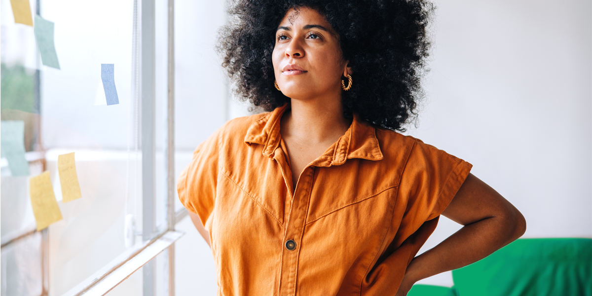 woman of color standing confidently and looking out the window