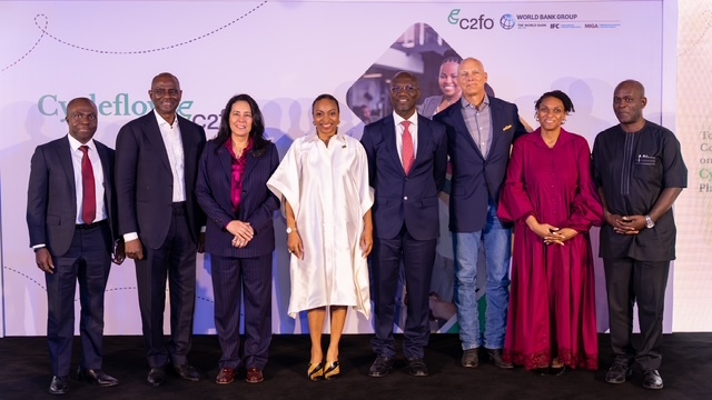 Nine people stand side by side at a formal Nigeria event, smiling and celebrating MSMEs on stage.